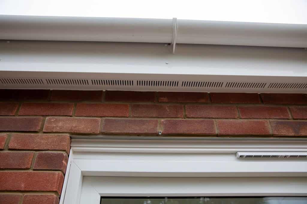 UPVC window and door ventilation grille on modern brick wall building.