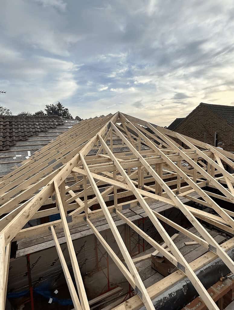 New roof framework under construction with timber trusses over residential property in UK.